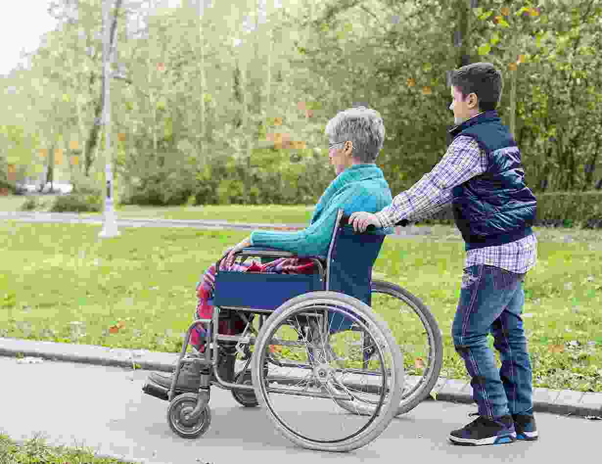 Un bénévole promène une résidente en fauteuil roulant dans un parc